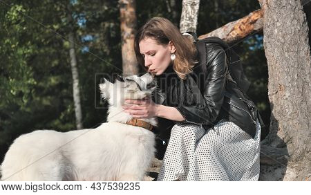 Young Woman Kissing Her Dog Yakutian Laika. Love To Pets And Affectionate Friendship. Walking Togeth