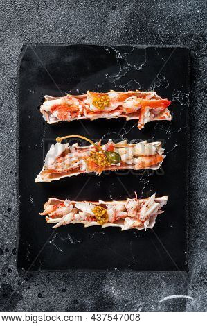 Crab Leg Meat In A Sheel With Herbs. Black Background. Top View