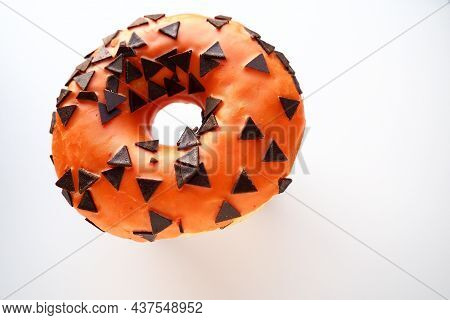 Halloween donut with orange frosting and chocolate triangles as a sweet decorative topping. Children