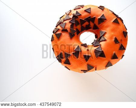 Halloween donut with orange frosting and chocolate triangles as a sweet decorative topping. Children