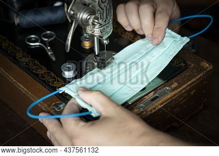 Stepwise Stitching Of Blue Fabric Medical Masks. Close-up Hands Holding A Ready-made Mask. The Conce