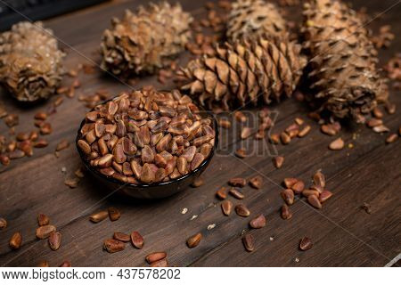 A Pine Cone And A Walnut Are Lying On A Wooden Table