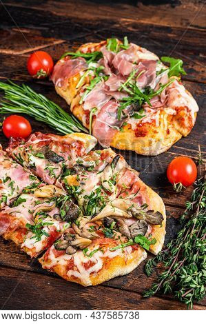 Sliced Pizza With Prosciutto Parma Ham, Arugula And Parmesan Cheese. Dark Wooden Background. Top Vie