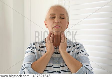 Mature Woman Doing Thyroid Self Examination Indoors