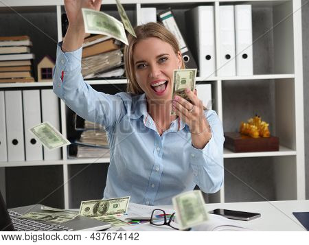 Portrait Of Happy Young Woman Rolling In Money, Flying Cash In Air, Abundance Of Banknotes. Office W