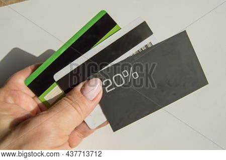 A Man's Hand Holding A Discount Card With A 20 Percent Discount And A Copy Of The Place And Several
