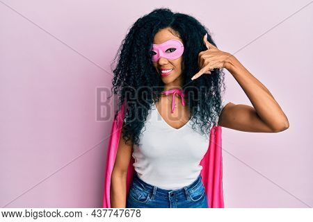 Middle age african american woman wearing super hero costume smiling doing phone gesture with hand and fingers like talking on the telephone. communicating concepts. 