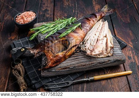 Cut Hot Smoked Fish On A Wooden Board With Rosemary. Dark Wooden Background. Top View
