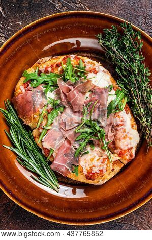 Pizza With Prosciutto Parma Ham, Arugula Salad And Parmesan Cheese In A Rustic Plate. Wooden Backgro