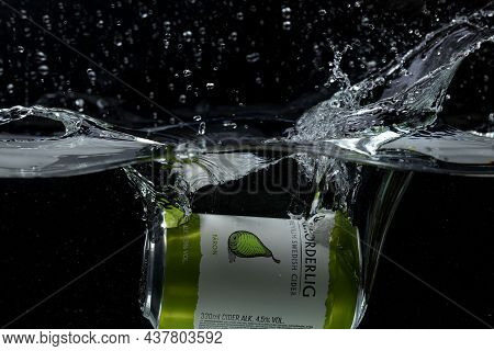 Close Up View Of Can Of Pear Sider Falling Into Water Isolation On Black Background. Sweden. Uppsala