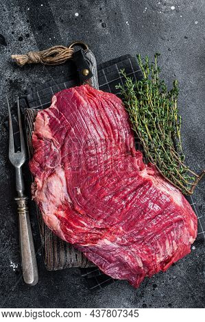 Uncooked Raw Flank Or Flap Beef Steak On Butcher Board. Black Background. Top View
