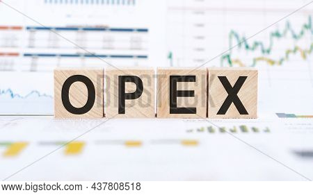 Word Opex Operational Expenditures Made With Wood Building Blocks On Background From Financial Graph