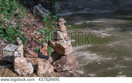 Balanced Stone Tower On Walkway Up The Mountain With Green Plants In The Background. No Focus, Speci
