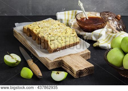 Sliced Apple And Coconut Oaf Cake On Wooden Cutting Board On Dark Background