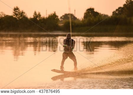 Adult Sporty Man Holds The Handle Of Cable And Balances With A Wakeboard On The Water