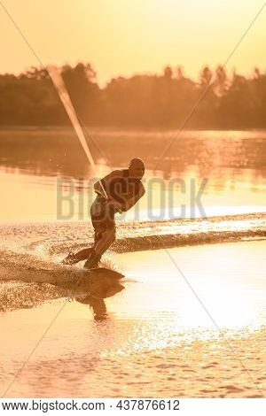 Adult Sporty Man Holds The Handle Of Cable And Masterfully Balances With A Wakeboard On The Water