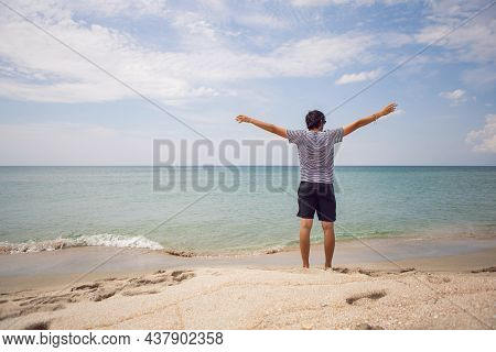 Guy In A Striped T-shirt And Shorts Is Standing On The Beach And Spread His Arms To The Side