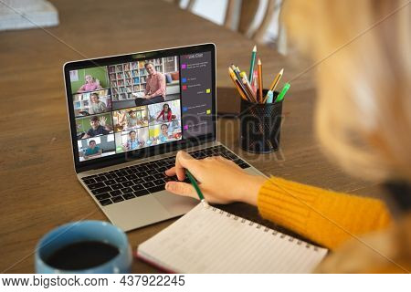 Caucasian woman using laptop for video call, with diverse elementary school pupils on screen. communication technology and online education, digital composite image.