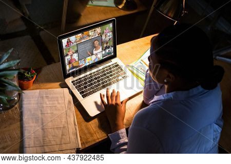 African american woman using laptop for video call, with diverse elementary school pupils on screen. communication technology and online education, digital composite image.