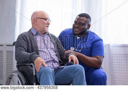 Caregiver And Old Man In A Wheelchair. Professional Nurse And Patient In A Nursing Home. Assistance,