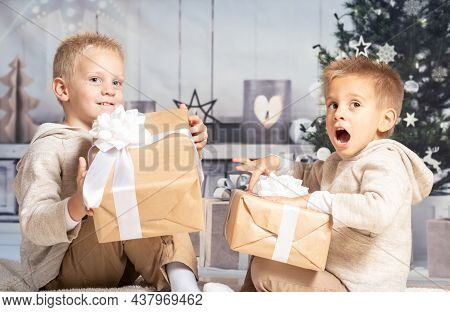 Twin Children At Home Receiving And Opening Christmas Presents.
