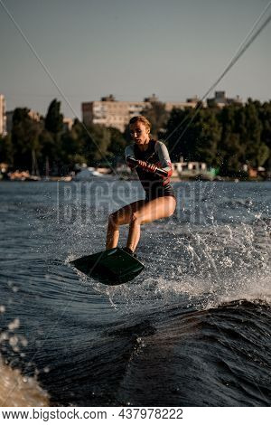 Beautiful Woman Holds Rope And Jumping With Wakeboard Over River Wave.