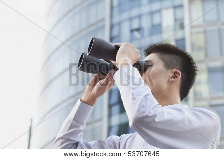 Young businessman looking through binoculars
