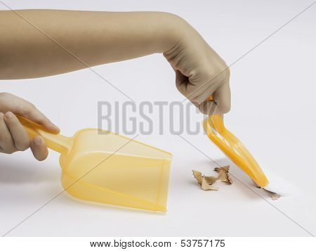 Hands Holding Broom And Dust Pan Sweeping Up Pencil Shavings On White Background