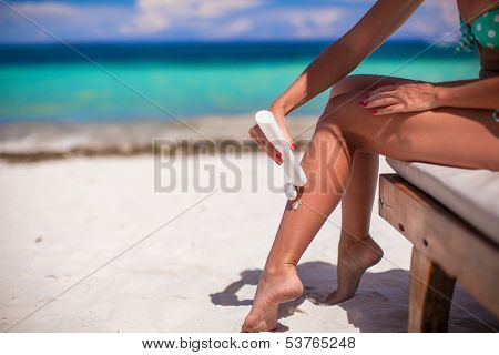 Young Woman Apply Cream On Her Smooth Tanned Legs At Tropical Beac