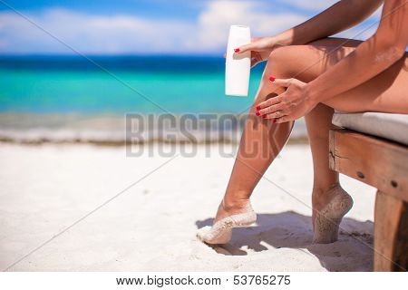 Young Woman Apply Cream On Her Smooth Tanned Legs At Tropical Beac