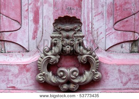 Door knoker on an old pink wodden door