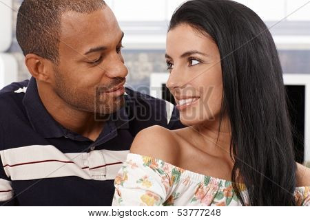 Loving mixed race couple looking at each other just about to kiss, smiling.
