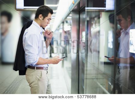 Businessman looking at his phone and waiting for subway in Beijing
