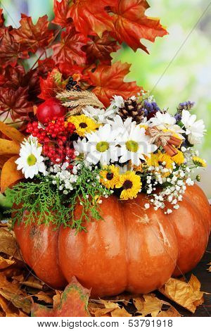 Beautiful autumn composition in pumpkin with yellow leaves on table on bright background