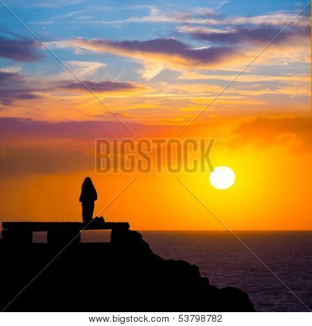 Ciutadella Menorca at Punta Nati orange sunset with girl backlight