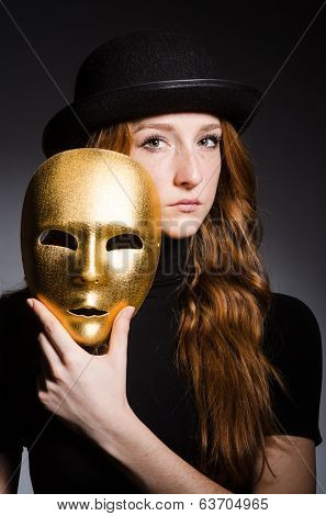 Redhead woman in hat  iwith mask in hypocrisy consept against grey background