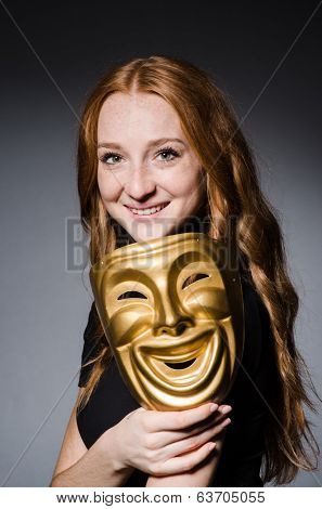Redhead woman iwith mask in hypocrisy consept against grey background