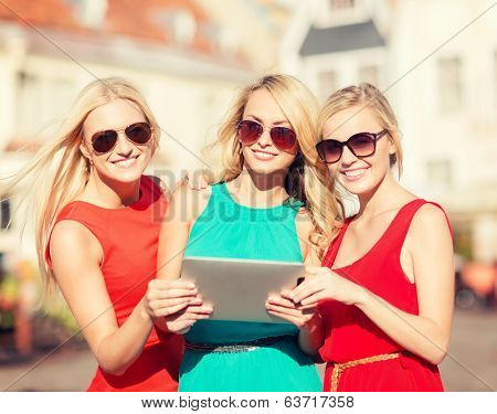 holidays and tourism concept - beautiful blonde girls toursits looking into tablet pc in the city