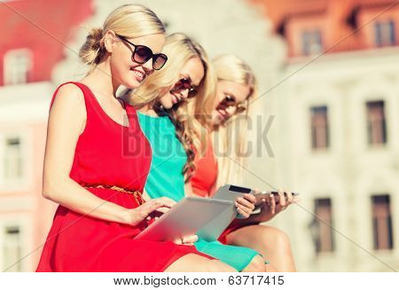 holidays and tourism concept - beautiful blonde girls toursits looking into tablet pc in the city