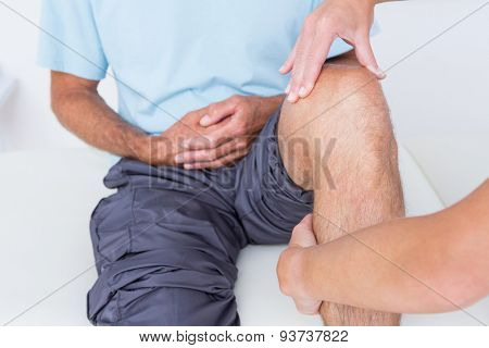 Doctor examining her patient knee in medical office