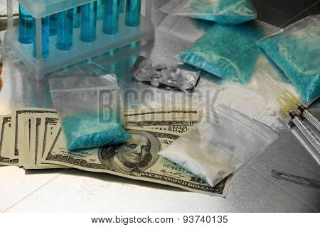 Drug laboratory: blue methamphetamine and money on table close up