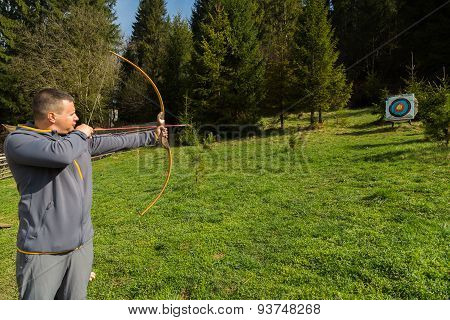 A man shoots a bow. Man engaged in archery.