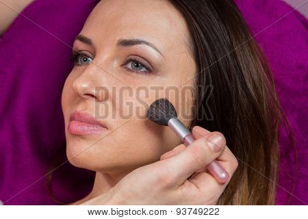 Makeup artist apply makeup on the face of the girl model.