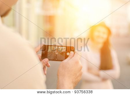 Touristic couple shooting on the modile phone at the city streets under sunlight.