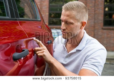 Man Looking For Scratches On His Car