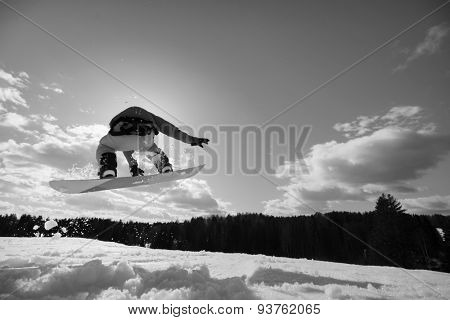 young man on the snowboard jumping over the slope in winter