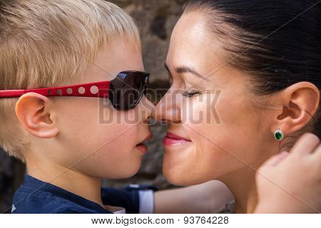 Mom and son. Baby and mom near a stone wall, hugging, kissing, show love.