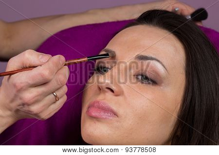 Makeup artist apply makeup on the face of the girl model.