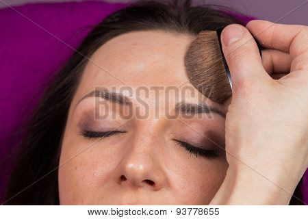 Work of make-up artist. Makeup artist apply makeup on the face of the girl model.