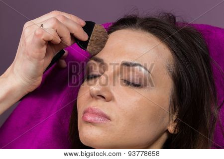 Work of make-up artist. Makeup artist apply makeup on the face of the girl model.